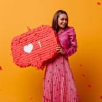 gorgeous joyful cheerful girl posing with red decorations her hands portrait brown haired woman pink outfit against wall confetti shape hearts